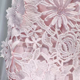 Close-up of white lace fabric held by a hand against a neutral background